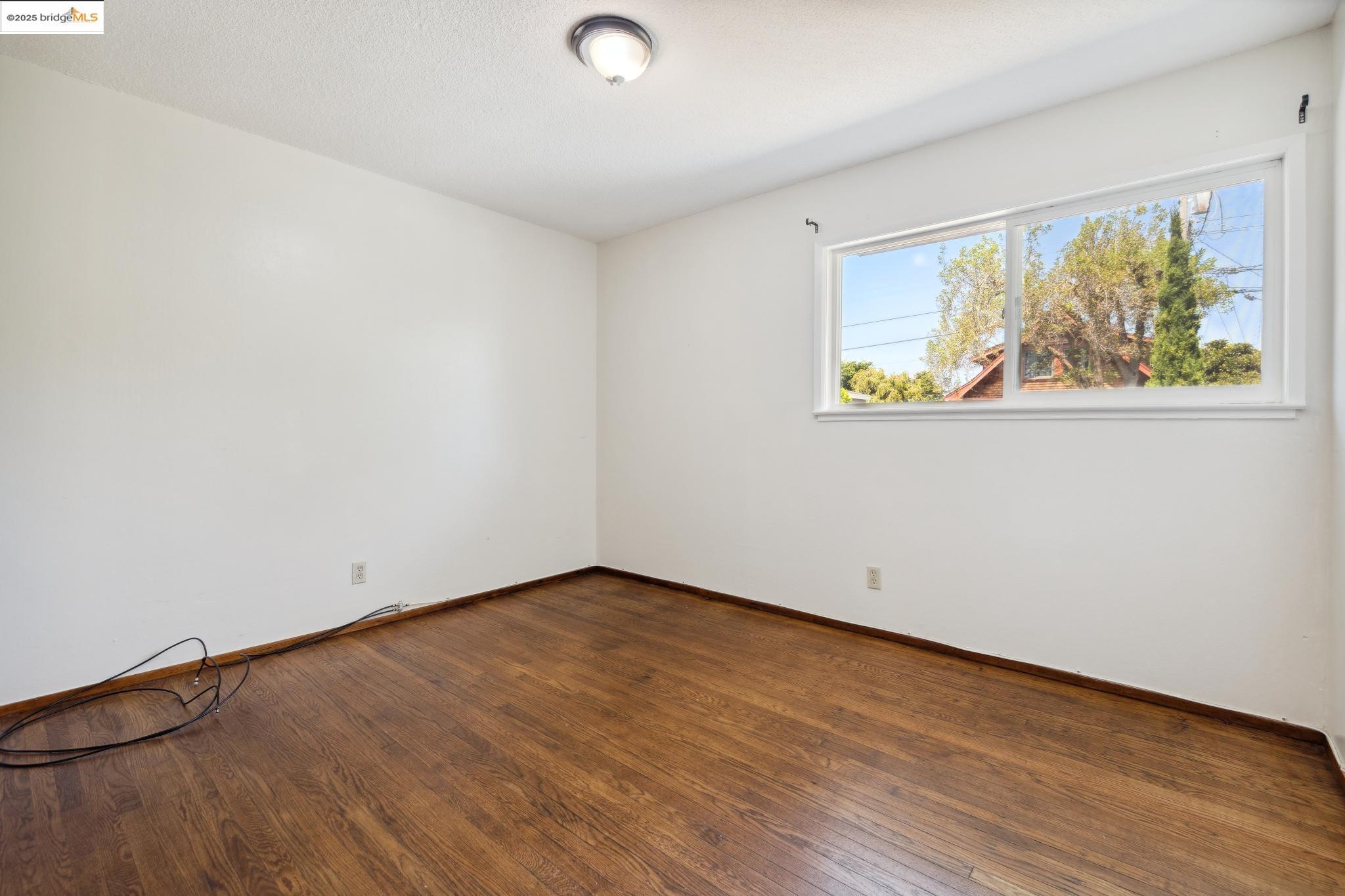 1612 Parker Street Berkeley, CA 94703 - Photo 12 of 16 an empty room with wooden floor and window