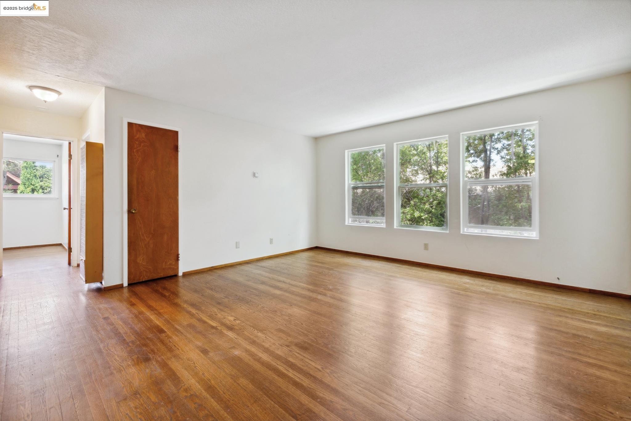 1612 Parker Street Berkeley, CA 94703 - Photo 9 of 16 an empty room with wooden floor and windows