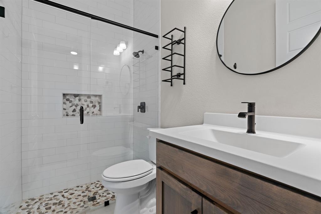 1821 Stonewall Road Argyle, TX 76226 - Photo 23 of 40 Modern bathroom featuring a walk-in shower with white subway tile, a recessed niche with pebble tile, and a glass enclosure with matte black hardware