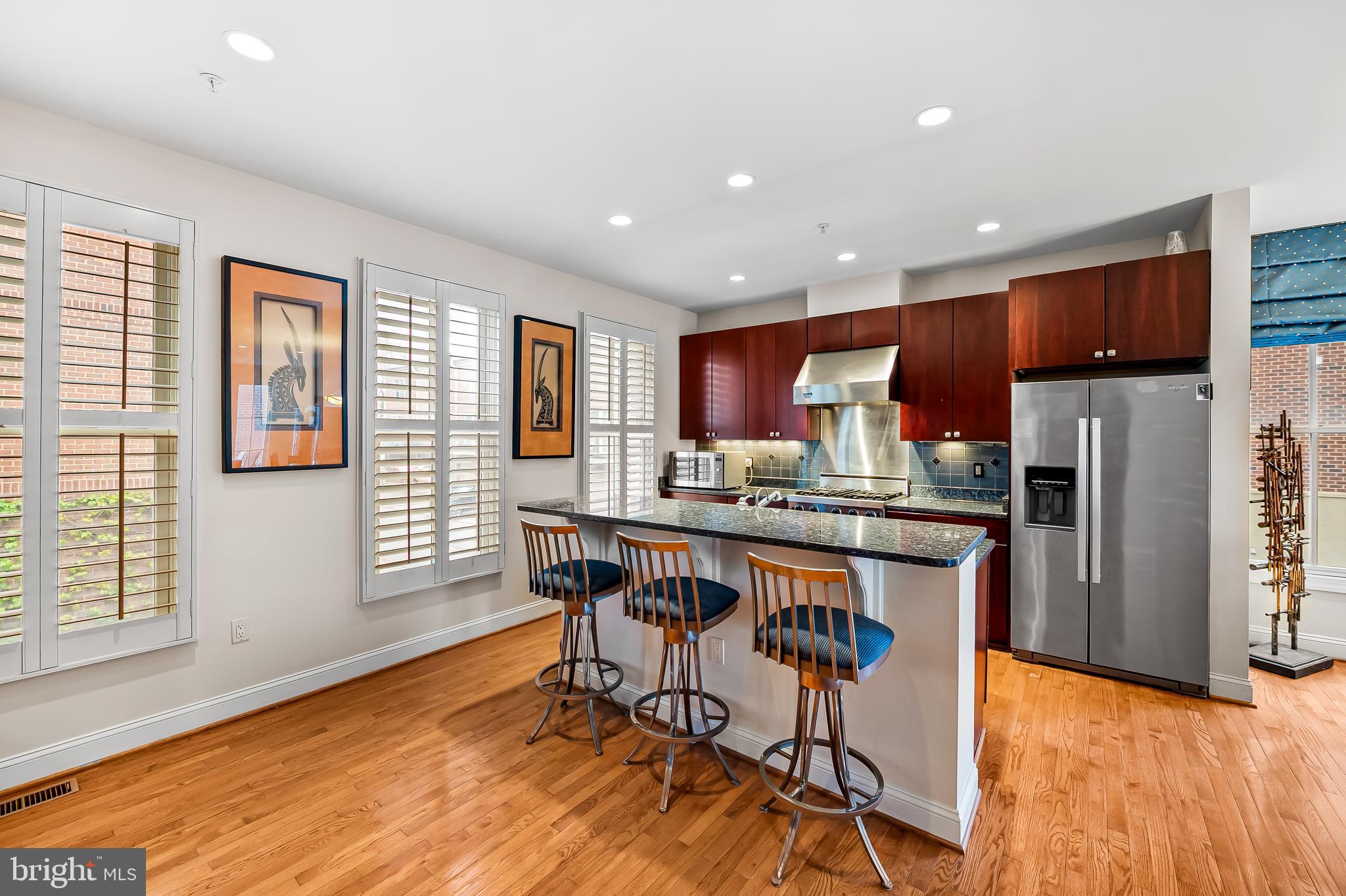 2323 Boston Street, Unit 6 Baltimore, MD 21224 - Photo 11 of 47 a kitchen with stainless steel appliances granite countertop a refrigerator a sink dishwasher a dining table and chairs with wooden floor