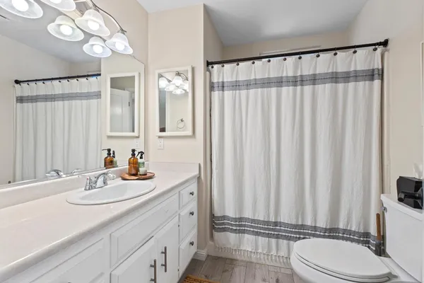 a bathroom with a sink a toilet a mirror and shower curtain