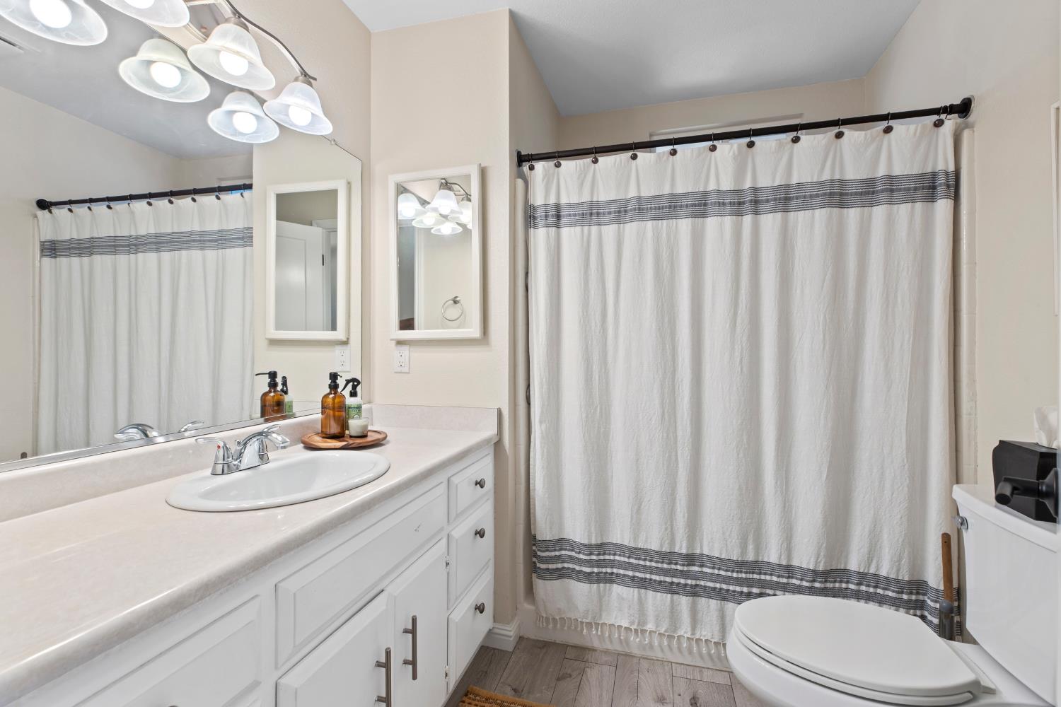 2841 Fowler Road, Unit 89 Ceres, CA 95307 - Photo 12 of 32 a bathroom with a sink a toilet a mirror and shower curtain