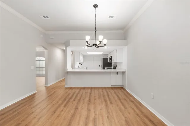 a view of a room with wooden floor chandelier and windows