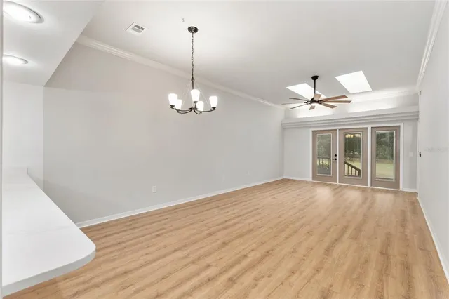 a view of empty room with wooden floor and chandelier