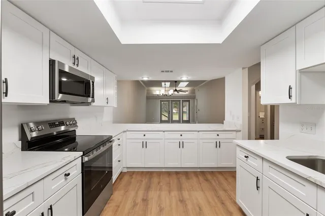 a kitchen with a sink dishwasher stove and white cabinets