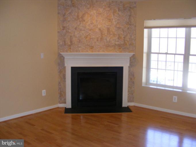 12000 Tralee Road, Unit 304 Lutherville-Timonium, MD 21093 - Photo 2 of 9 an empty room with wooden floor and fireplace