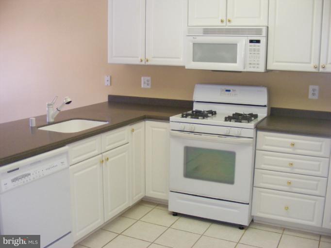12000 Tralee Road, Unit 304 Lutherville-Timonium, MD 21093 - Photo 6 of 9 a kitchen with granite countertop white cabinets and white stove