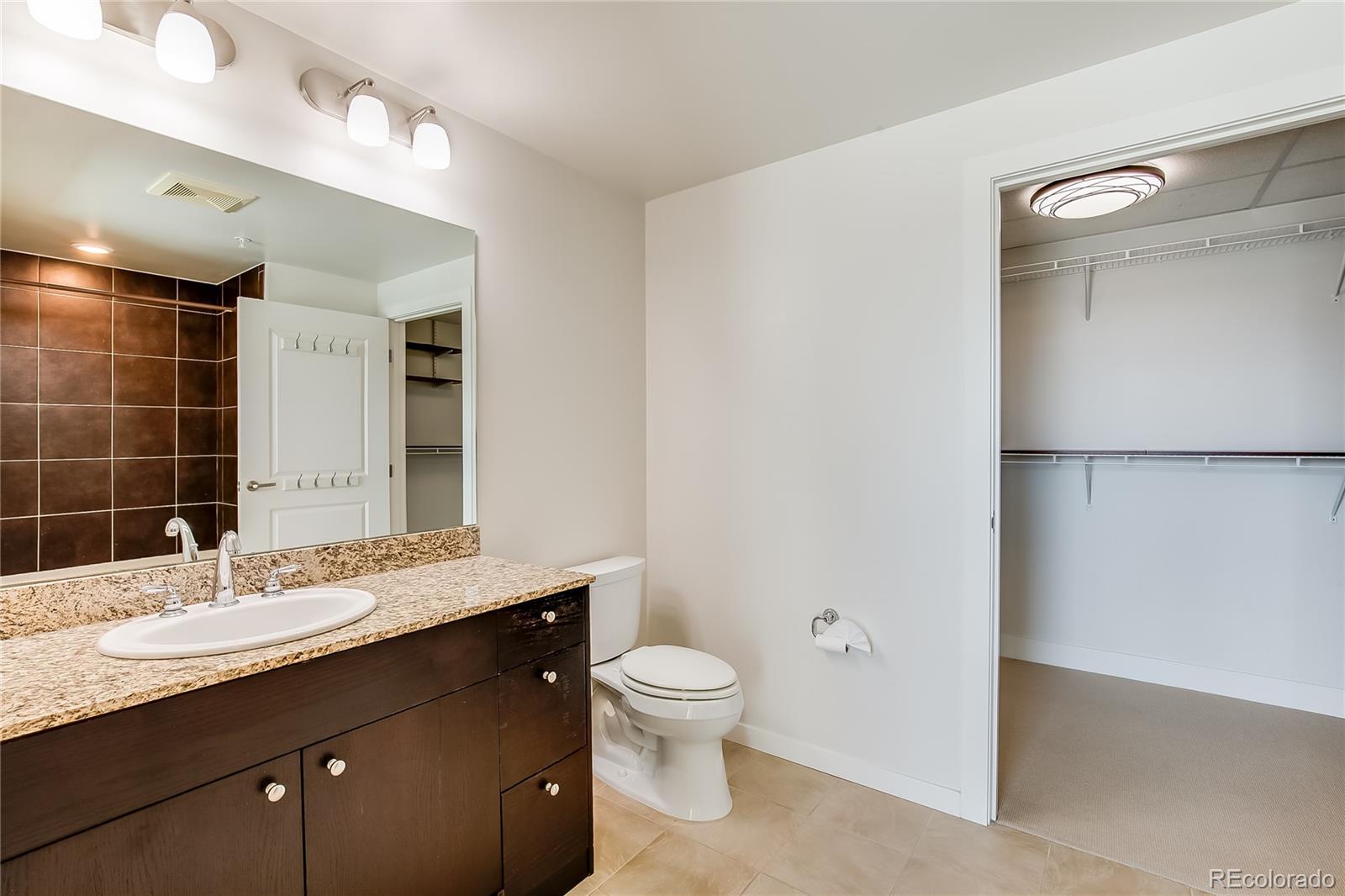 2001 Lincoln Street, Unit 1024 Denver, CO 80202 - Photo 12 of 19 a bathroom with a granite countertop sink toilet a large mirror and shower