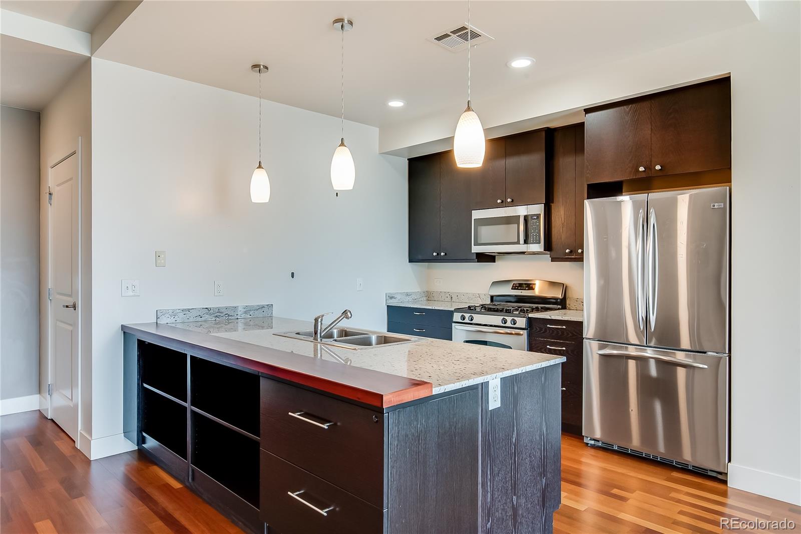 2001 Lincoln Street, Unit 1024 Denver, CO 80202 - Photo 3 of 19 a kitchen with kitchen island stainless steel appliances a sink cabinets and wooden floor