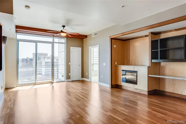 a view of an empty room with a window and wooden floor