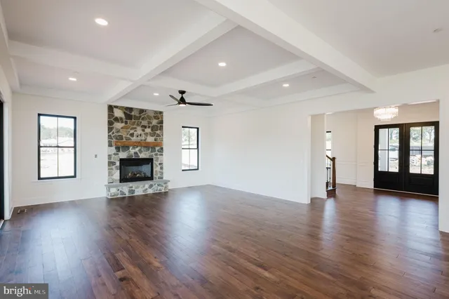 a large kitchen with stainless steel appliances granite countertop a stove a sink a refrigerator and white cabinets with wooden floor