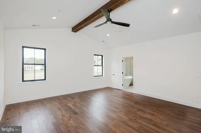 a view of an empty room with wooden floor and a ceiling fan