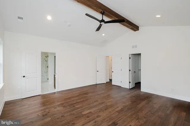 a view of an empty room with wooden floor and a ceiling fan