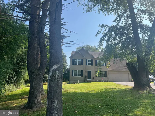 a front view of a house with a yard deck and a large tree