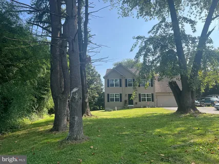 a view of house with a big yard plants and large trees