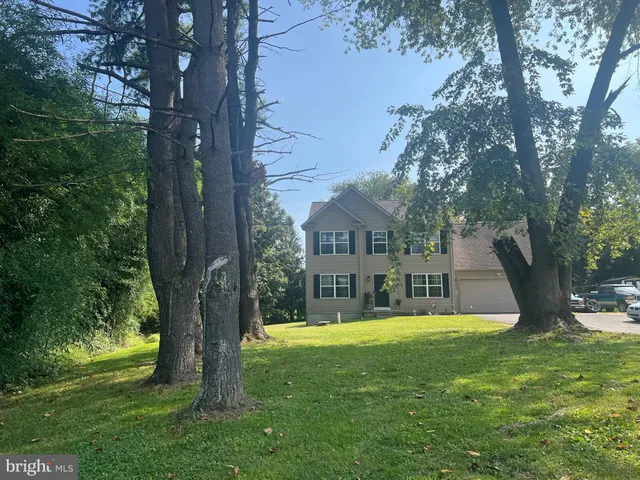 a view of house with a big yard plants and large trees
