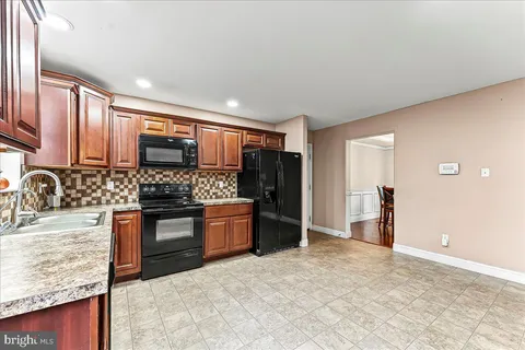 a large kitchen with stainless steel appliances granite countertop a refrigerator stove and sink