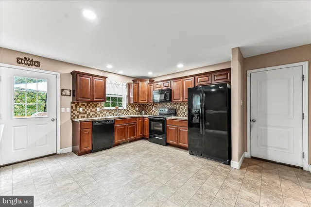 a large kitchen with stainless steel appliances granite countertop a refrigerator and a stove top oven