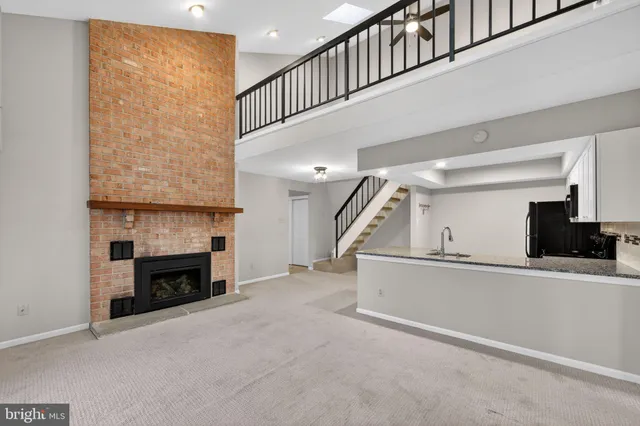 a view of an empty room with fireplace stairs and windows