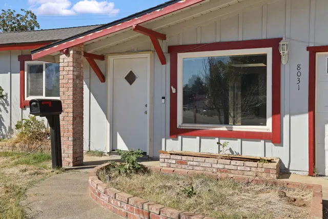 a view of a house with a porch and floor to ceiling windows