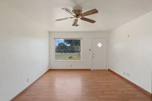 an empty room with a ceiling fan and windows