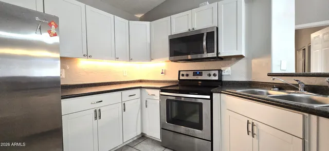 a kitchen with white cabinets and stainless steel appliances