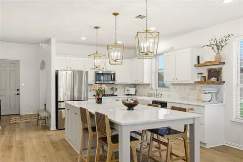 a kitchen with stainless steel appliances granite countertop a sink a stove a refrigerator and island with wooden floor