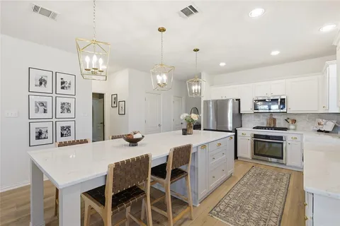 a large kitchen with granite countertop a stove a sink a dining table and chairs