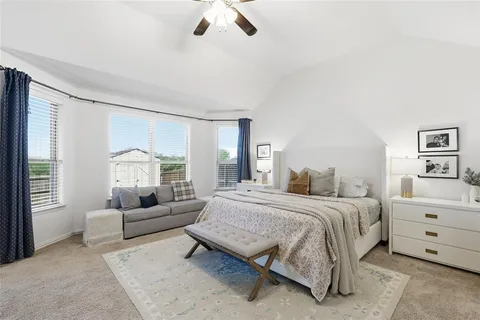 a spacious bedroom with a bed a couch and a large window