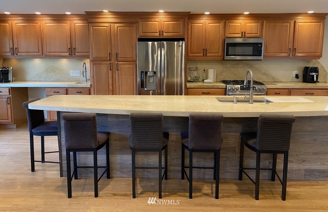 14530 166th Place Southeast Renton, WA 98059 - Photo 5 of 30 a kitchen with stainless steel appliances kitchen island granite countertop a table chairs microwave and sink
