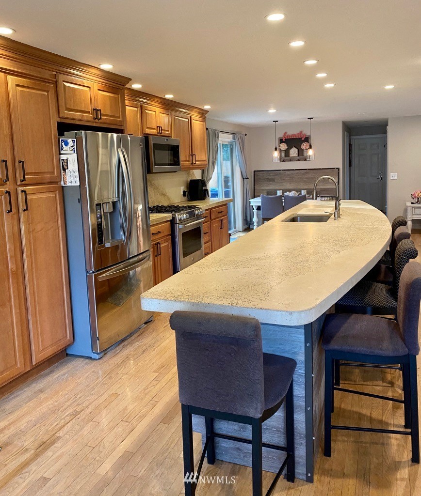 14530 166th Place Southeast Renton, WA 98059 - Photo 8 of 30 a kitchen with stainless steel appliances a dining table chairs refrigerator and stove