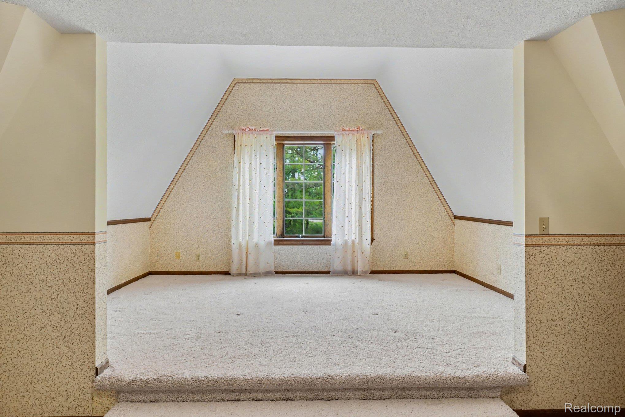 4425 North Henderson Road Davison, MI 48423 - Photo 17 of 43 Carpeted room featuring a prominent window, sloped ceilings, a decorative wallpaper accent, and baseboard trim