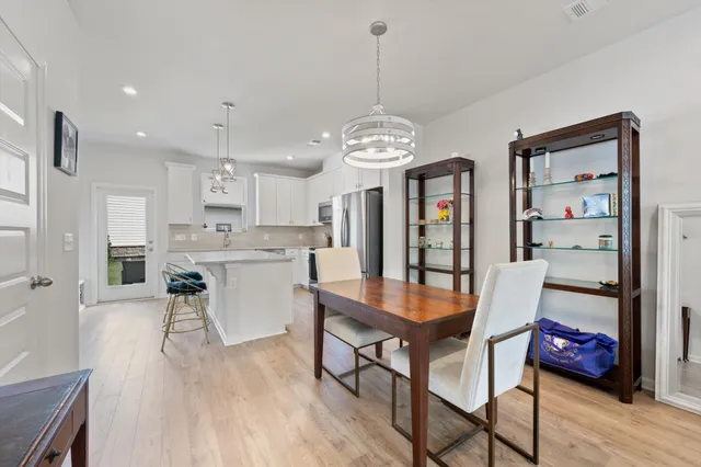 a dining room with stainless steel appliances kitchen island granite countertop furniture and wooden floor