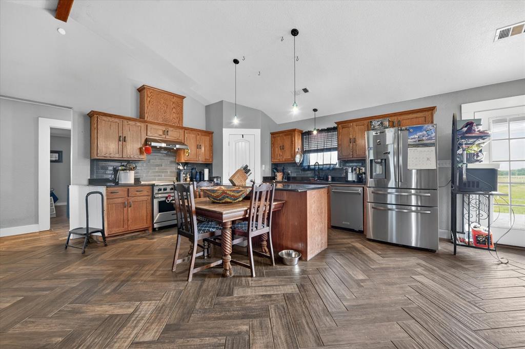 7145 Donald Road Krum, TX 76249 - Photo 10 of 35 a kitchen view with stainless steel appliances kitchen island granite countertop a table chairs and a refrigerator