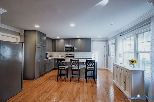 a kitchen with stainless steel appliances a dining table chairs stove refrigerator and cabinets