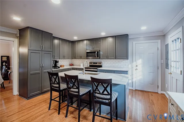 a kitchen with stainless steel appliances granite countertop a dining table chairs refrigerator and microwave