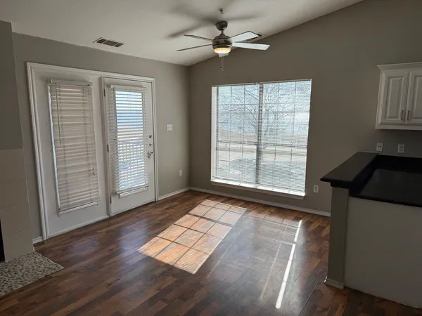 a view of empty room with wooden floor and fan