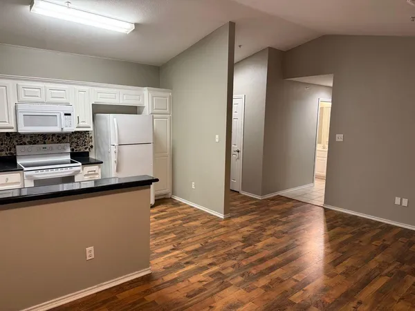a kitchen with granite countertop a refrigerator and a stove top oven