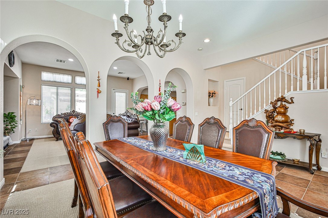 7643 Cascade Ridge Court Las Vegas, NV 89113 - Photo 8 of 46 Tiled dining area with arched walkways, a chandelier, recessed lighting, and stairway