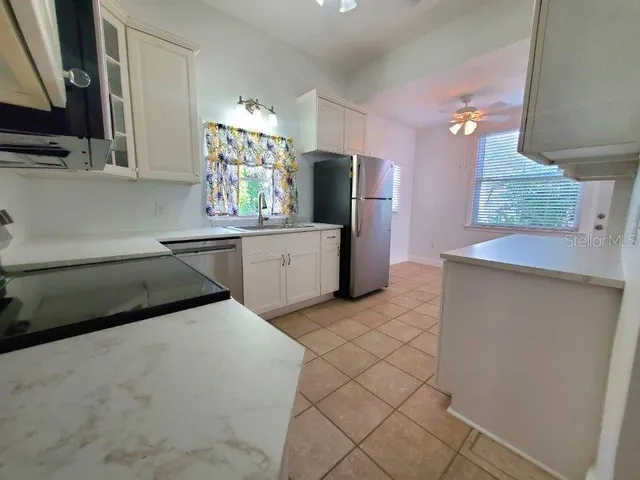 a kitchen with granite countertop a refrigerator and a stove top oven