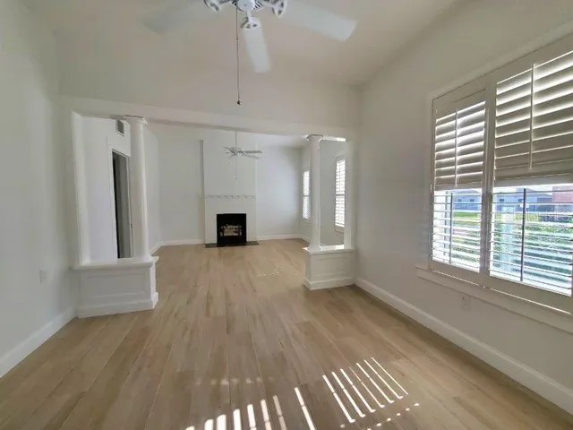 a view of empty room with wooden floor and fan