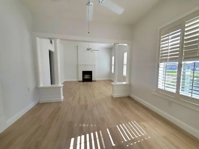 a view of an empty room with wooden floor and a window