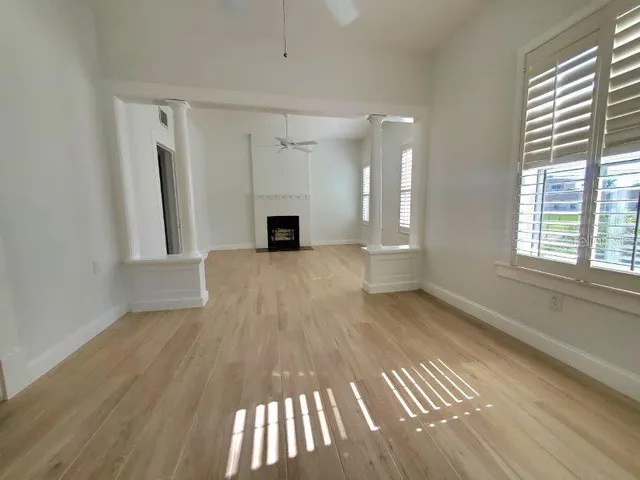 a view of an empty room with a window and wooden floor