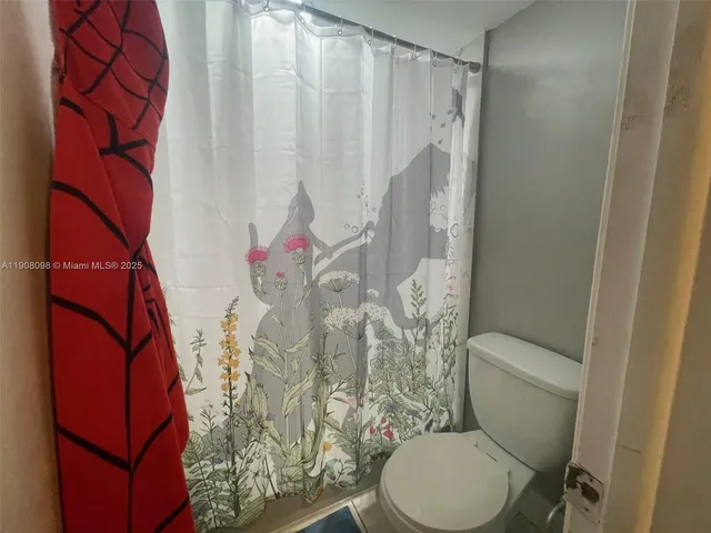 a white toilet sitting next to a shower curtain