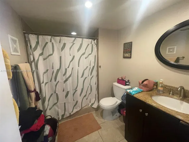 a bathroom with a granite countertop sink mirror vanity and toilet