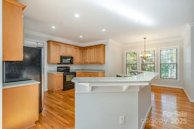 a kitchen with stainless steel appliances kitchen island granite countertop a refrigerator a stove top oven a sink with island and chairs