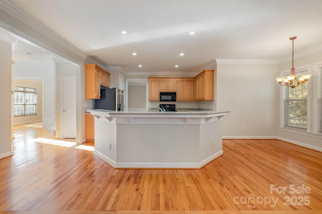 a view of a kitchen with kitchen island wooden floors stainless steel appliances and window