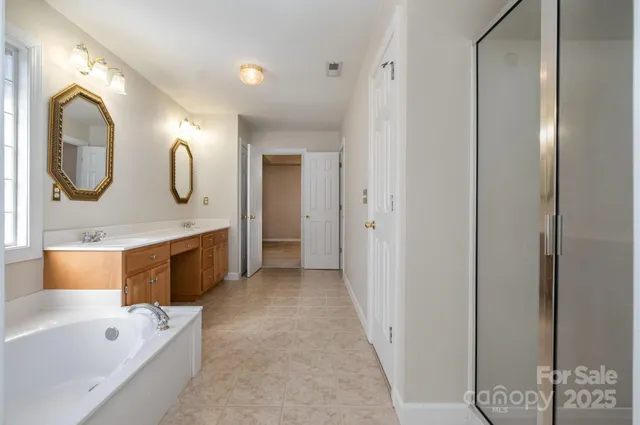 a spacious bathroom with a tub a double vanity sink and mirror