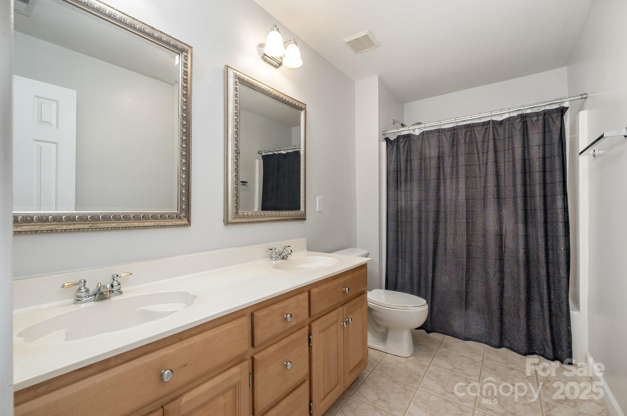 1930 Copperplate Road Charlotte, NC 28262 - Photo 29 of 43 a bathroom with a double vanity sink toilet mirror and shower