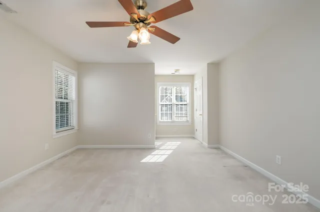 an empty room with windows and fan